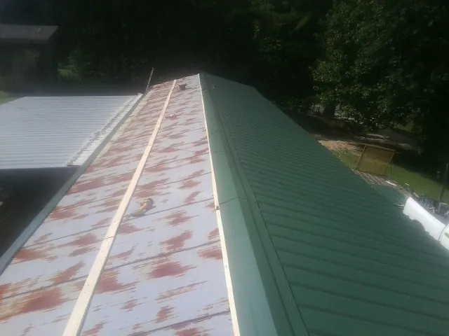 Old rusted panels beside newly installed green metal roofing — Wind Damage Roof Repair by Roofing Brothers in Park Ridge