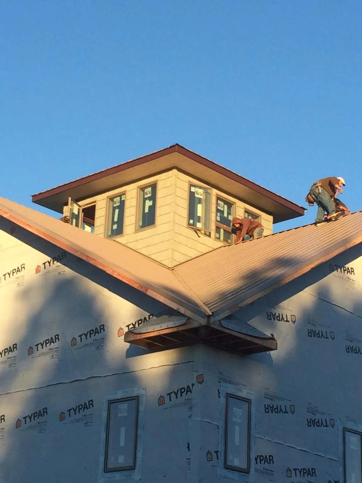 Roofers working around a rooftop cupola on a new metal roof at sunset — Roof Waterproofing in Park Ridge by Roofing Brothers